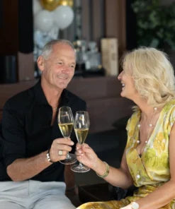 Man and woman clinking champagne glasses in a celebratory setting.