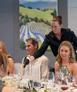 Group of people at a formal event with a scenic painting in the background