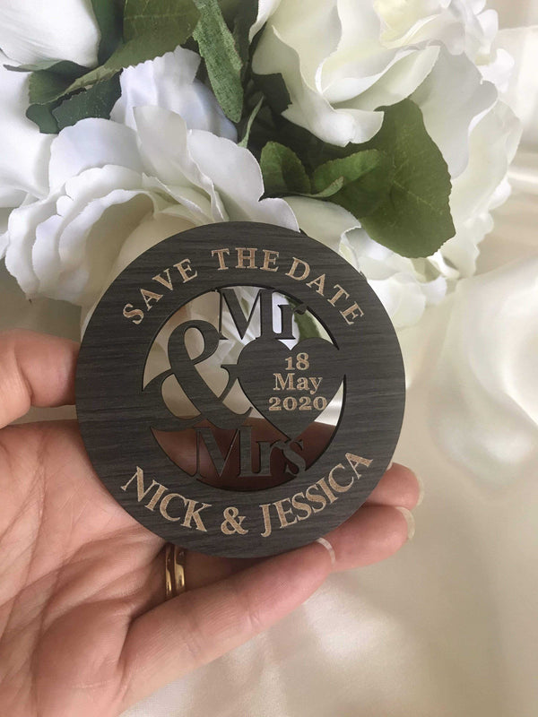 Wooden 'Save the Date' ring holder with personalized text held against a floral background
