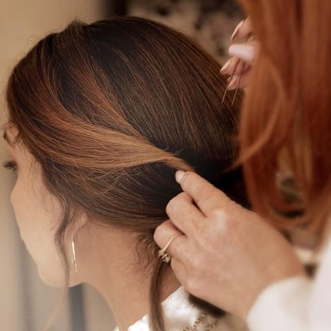 Person getting their hair styled by another person with a neutral background