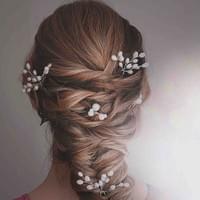 Woman with braided hair adorned with pearl hair accessories against a neutral background