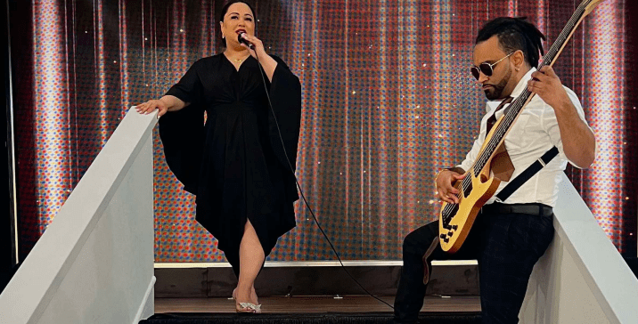 Two musicians performing on a stage with a woman singing and a man playing guitar.