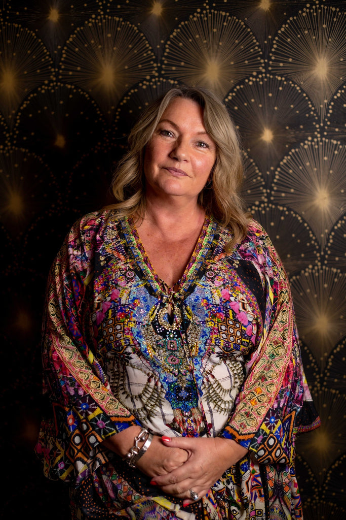 Woman wearing a colorful patterned dress against a decorative background