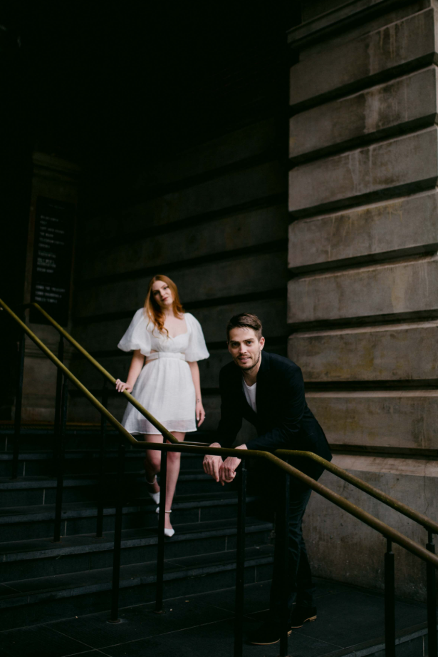 Man and woman standing on a staircase in an urban setting
