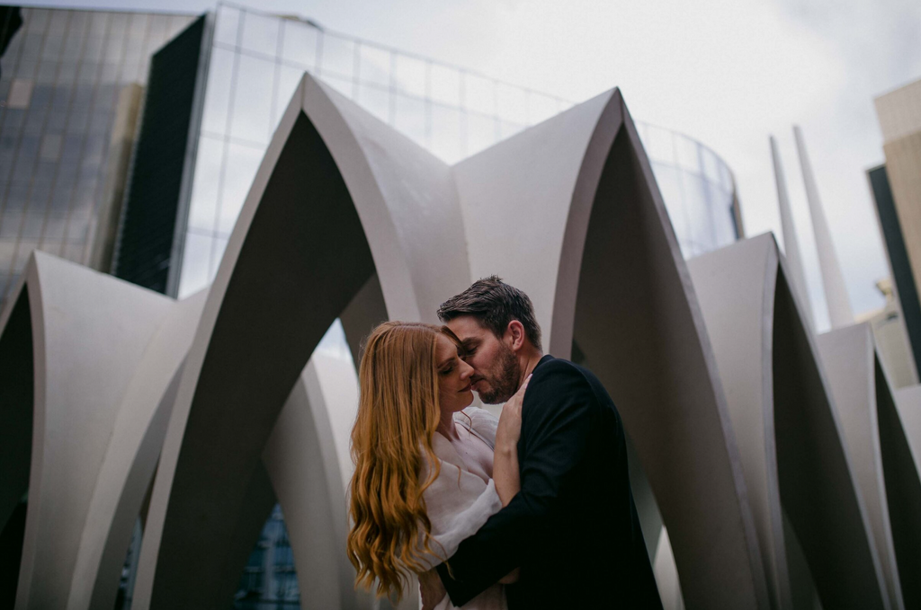 Couple embracing in front of modern architectural structures