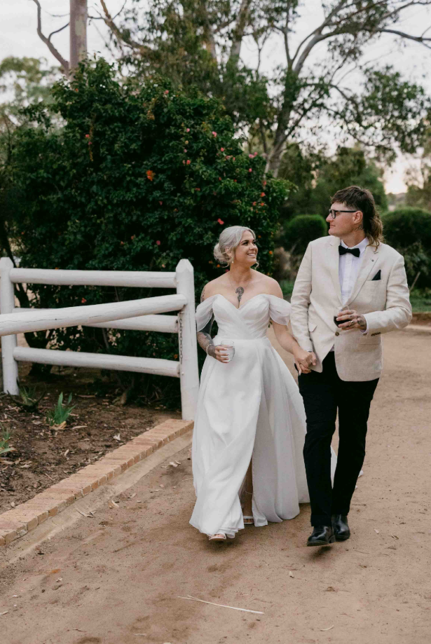 Man and woman walking together outdoors, likely on a wedding day.