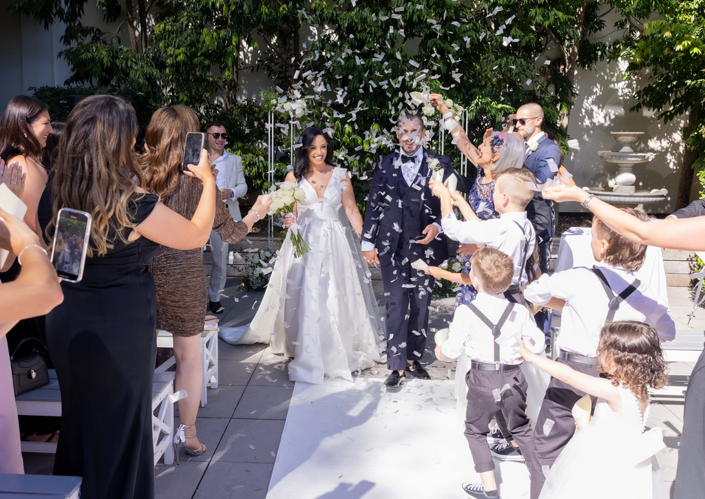 Wedding ceremony with bride and groom walking down the aisle, surrounded by guests and children.
