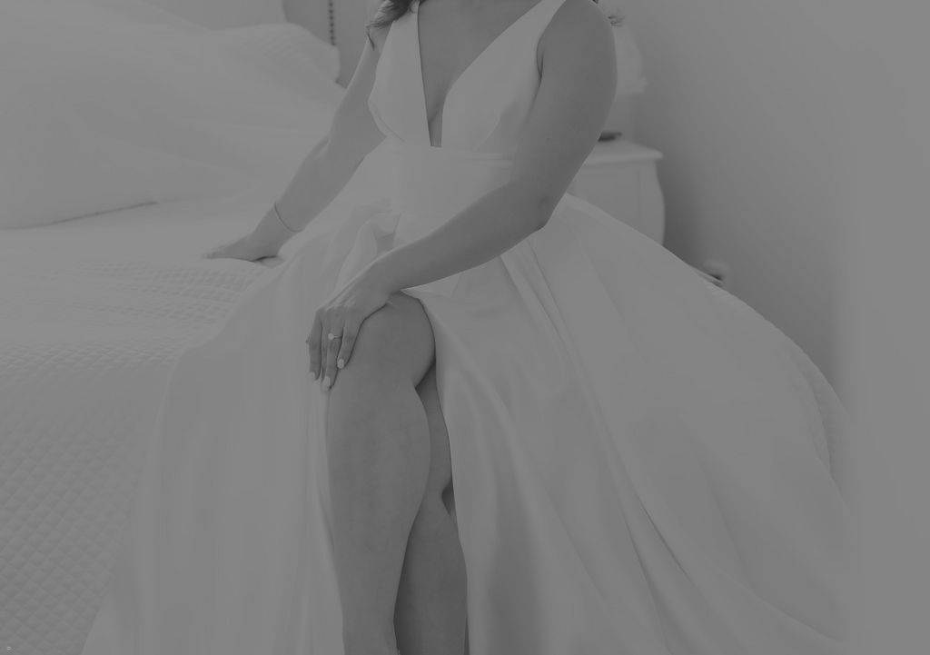 Person in a white wedding dress sitting on a bed.