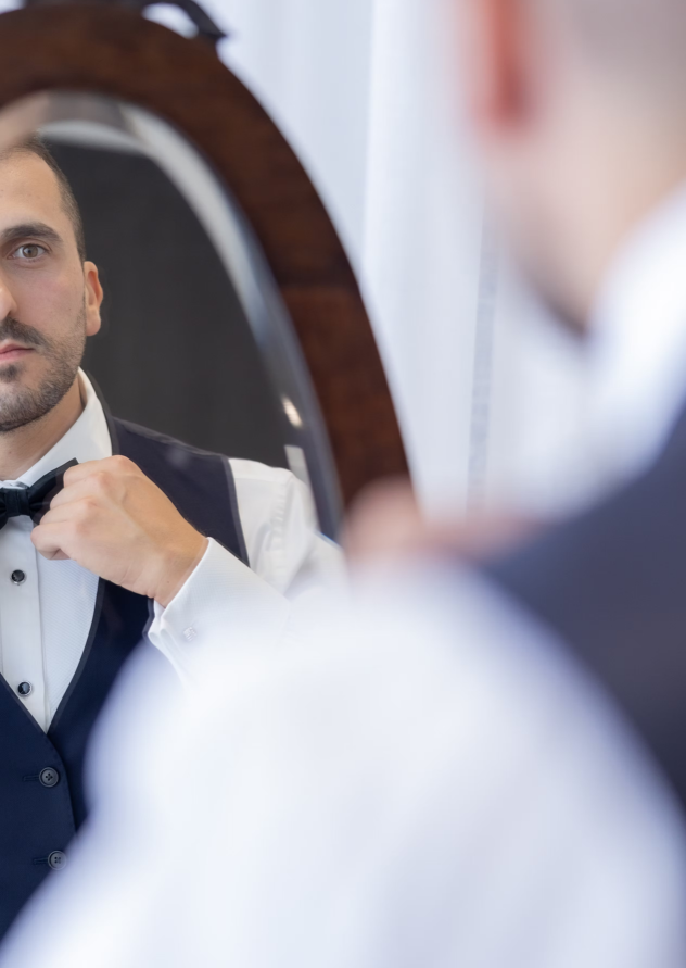 Man adjusting his bow tie in front of a mirror