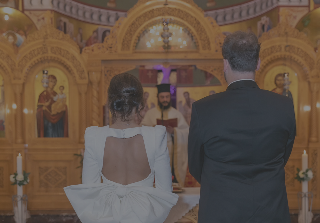 Couple in a church during a wedding ceremony with a priest in the background.