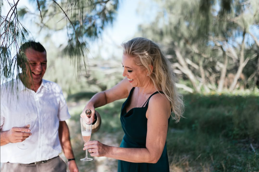 Man and woman enjoying a drink outdoors with trees in the background