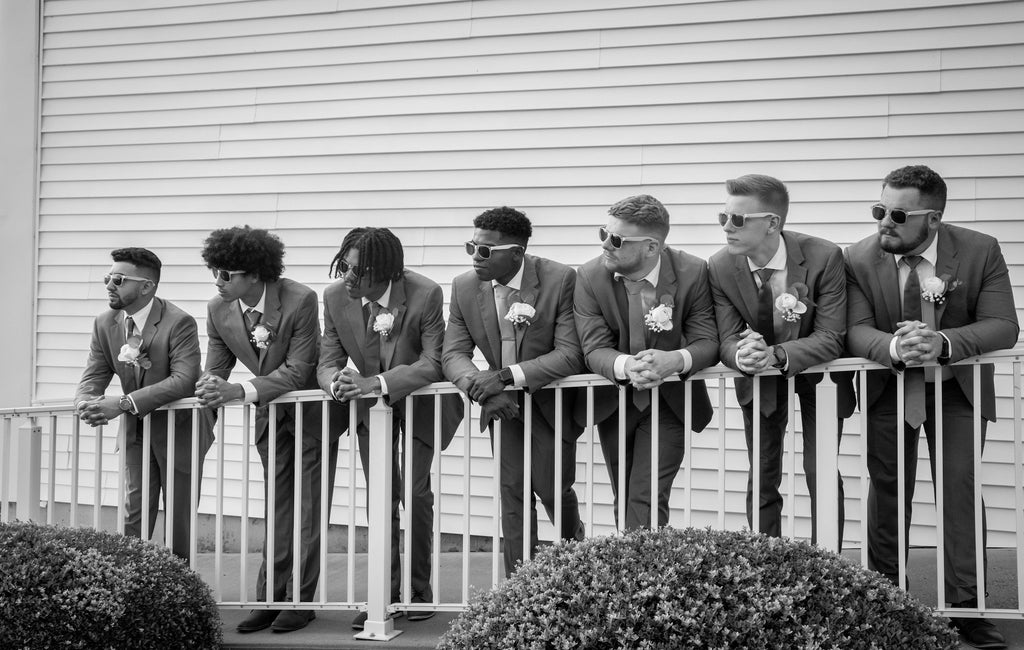 Groomsmen in suits standing on a balcony with a neutral background