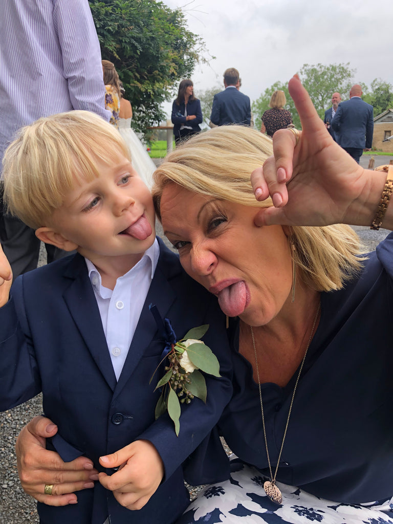Woman and child making silly faces outdoors with people in the background