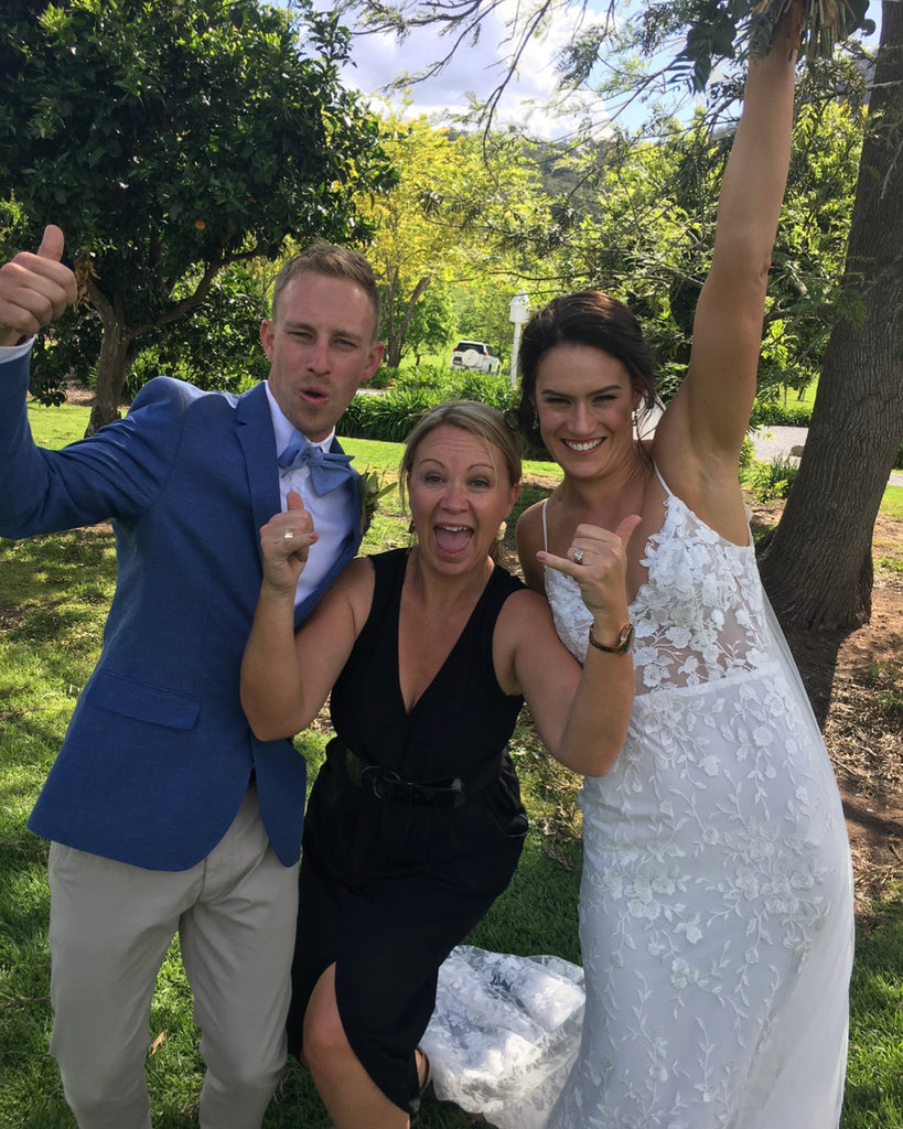 Three people celebrating outdoors with trees and grass in the background