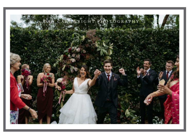 Wedding couple celebrating with guests outdoors, surrounded by greenery.